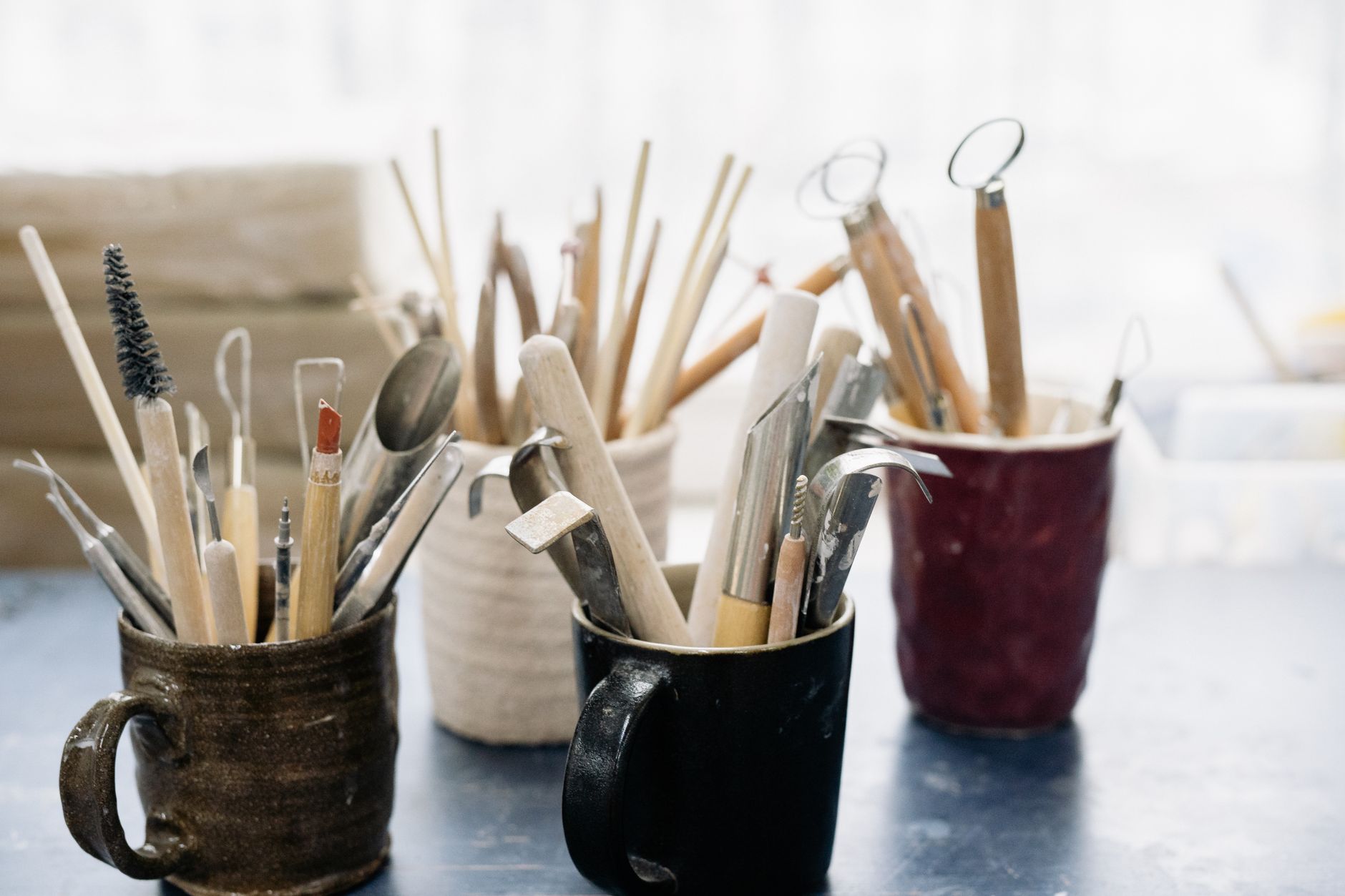 Outils de sculpture et de modelage rangés dans des mugs en céramique